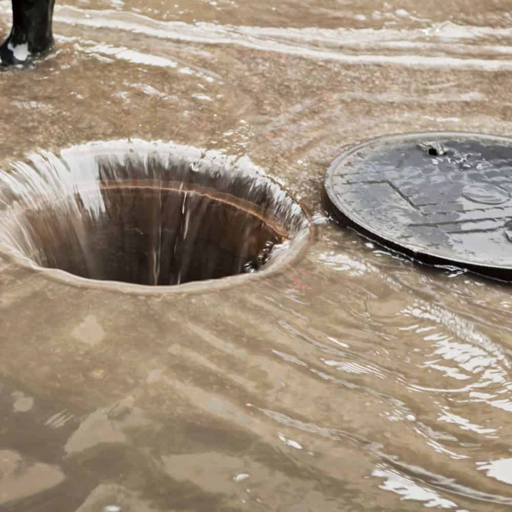 Flooded drain cover with water overflow, drainage repair service. Better Drains Reading Soakaway Installation